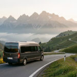 Préparer un road trip en France : 8 préparatifs indispensables Véhicule de voyage discret roulant sur une route panoramique française, avec des montagnes lointaines baignées par la lumière douce du matin.